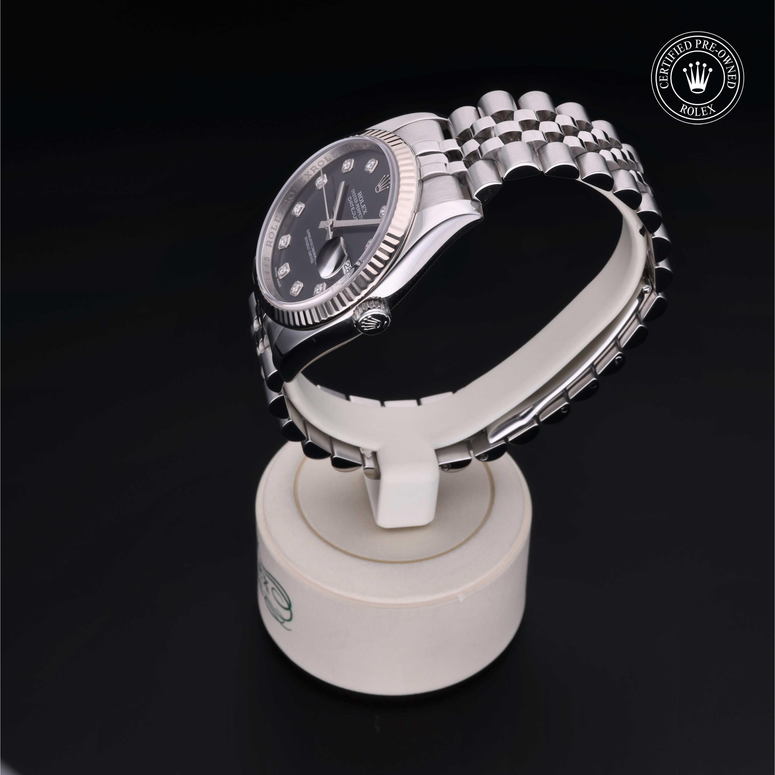 Rolex Certified Pre-Owned luxury watch with a silver metal bracelet and black dial, displayed on a white watch stand, highlighting fine craftsmanship and elegant design.