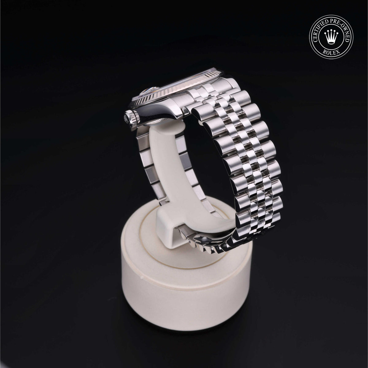 Silver stainless steel Rolex watch displayed on a white stand with a black background, featuring a 