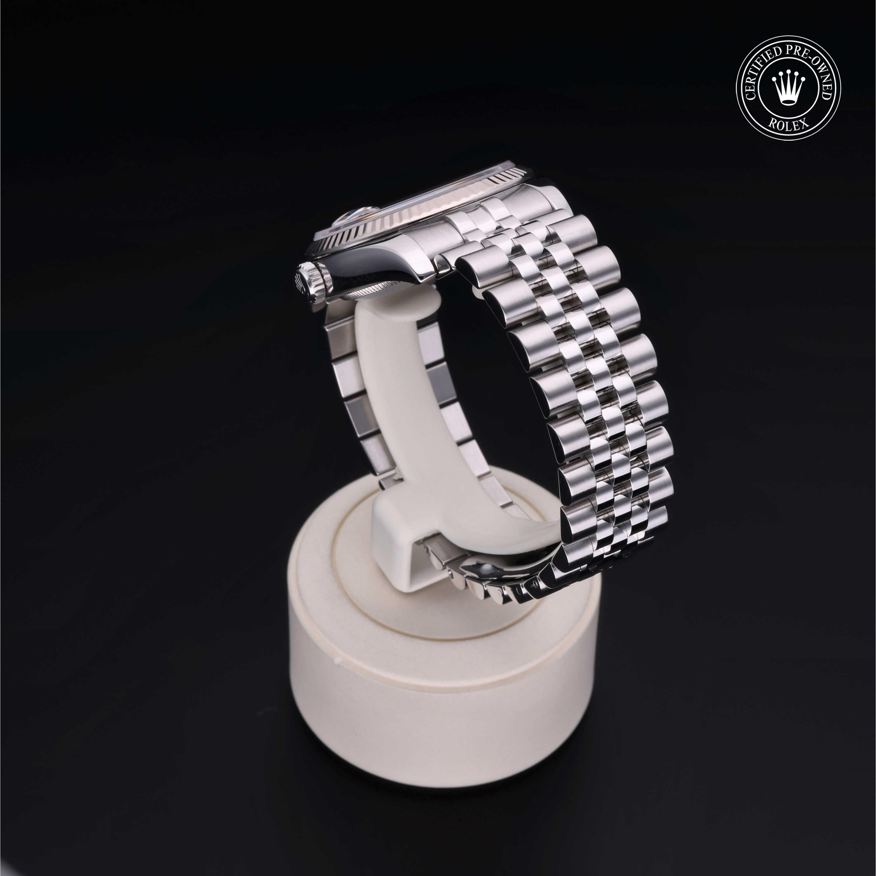 Silver stainless steel Rolex watch displayed on a white stand with a black background, featuring a 