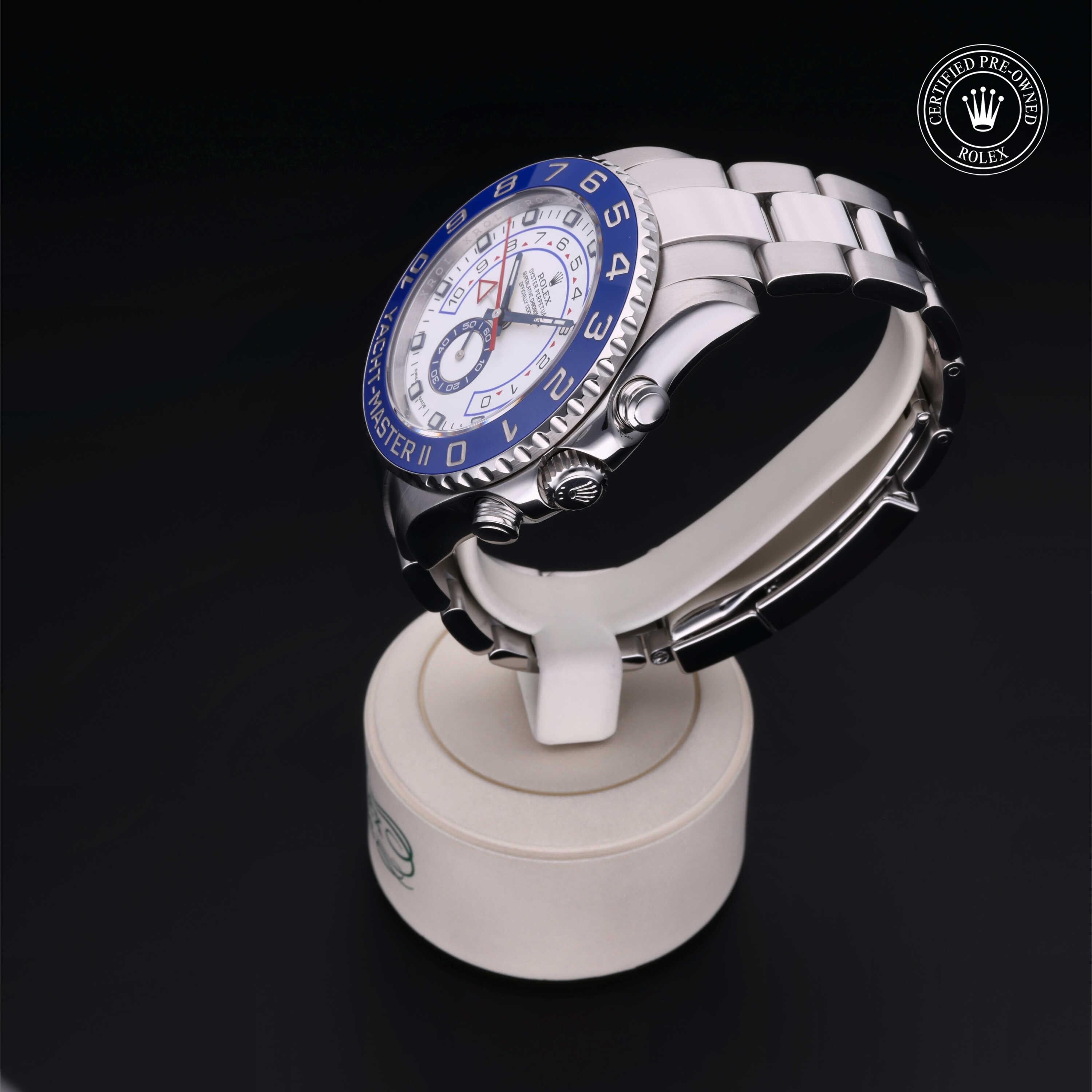 Silver Rolex Yacht-Master II watch with a blue bezel and white dial displayed on a white stand, featuring a 