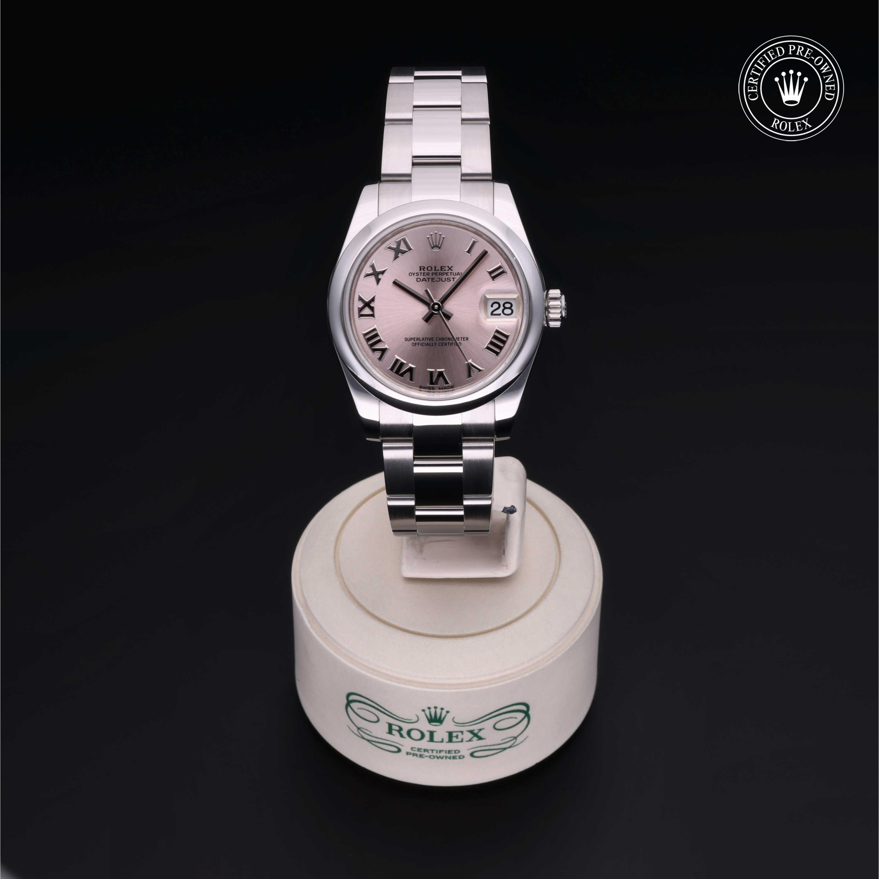 Rolex luxury watch with a stainless steel bracelet and dark dial featuring Roman numerals, displayed on a branded stand with a Certified Pre-Owned Rolex emblem.