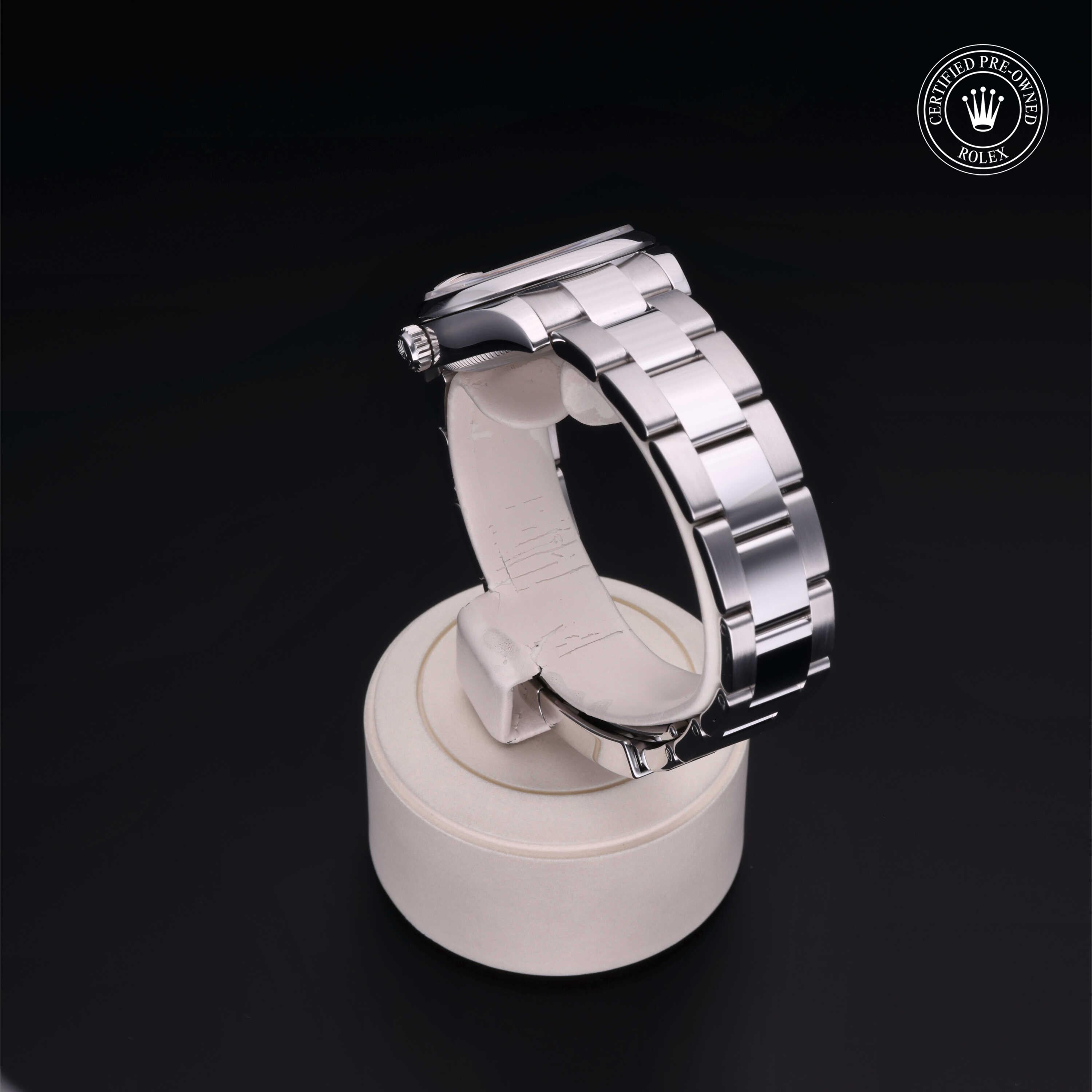Silver stainless steel Rolex watch band displayed on a white stand against a black background with a certified pre-owned Rolex logo in the corner, showcasing luxury watches.