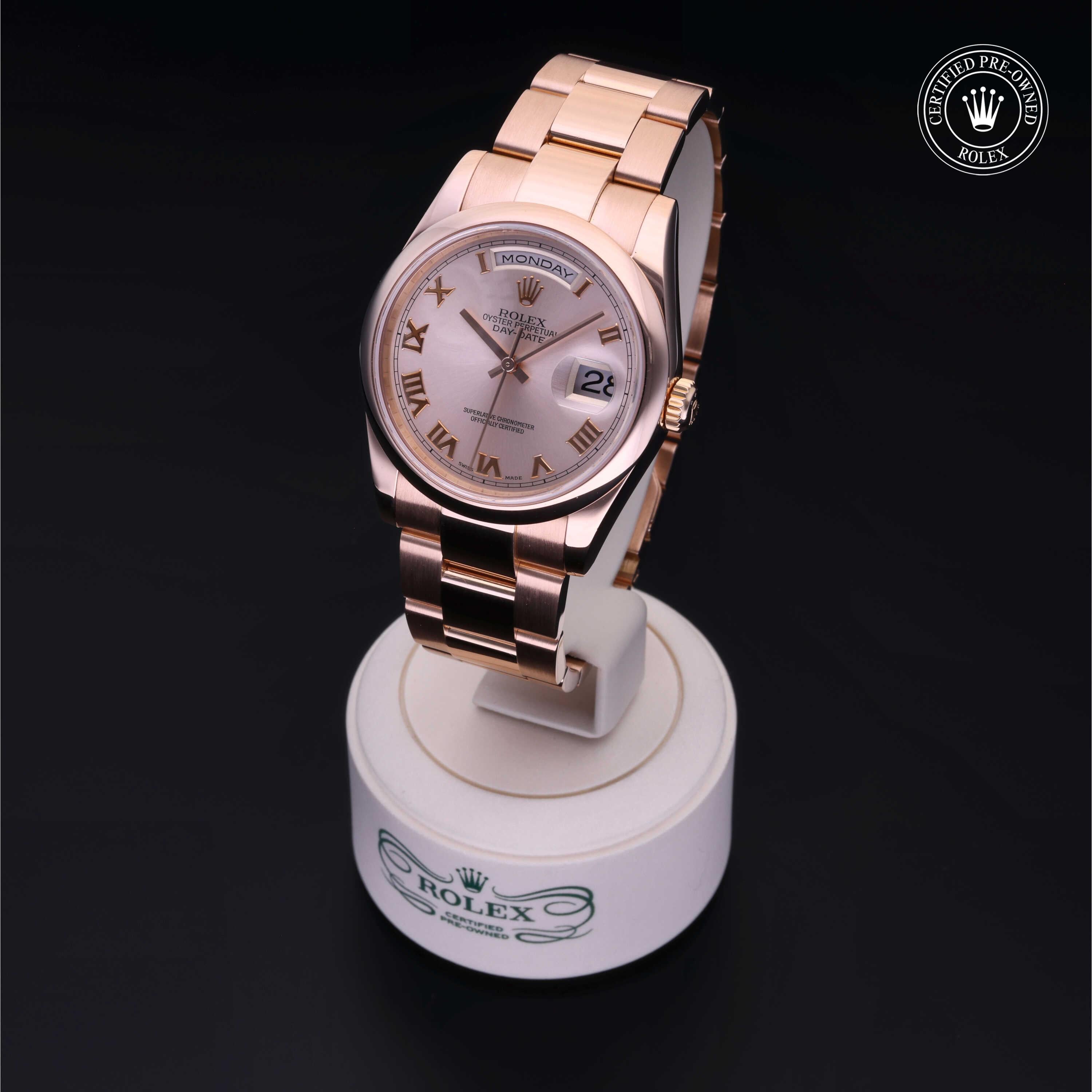 Rose gold Rolex watch with Roman numeral markers and day-date display on a white stand, highlighting luxury craftsmanship and Rolex Certified Pre-Owned status.
