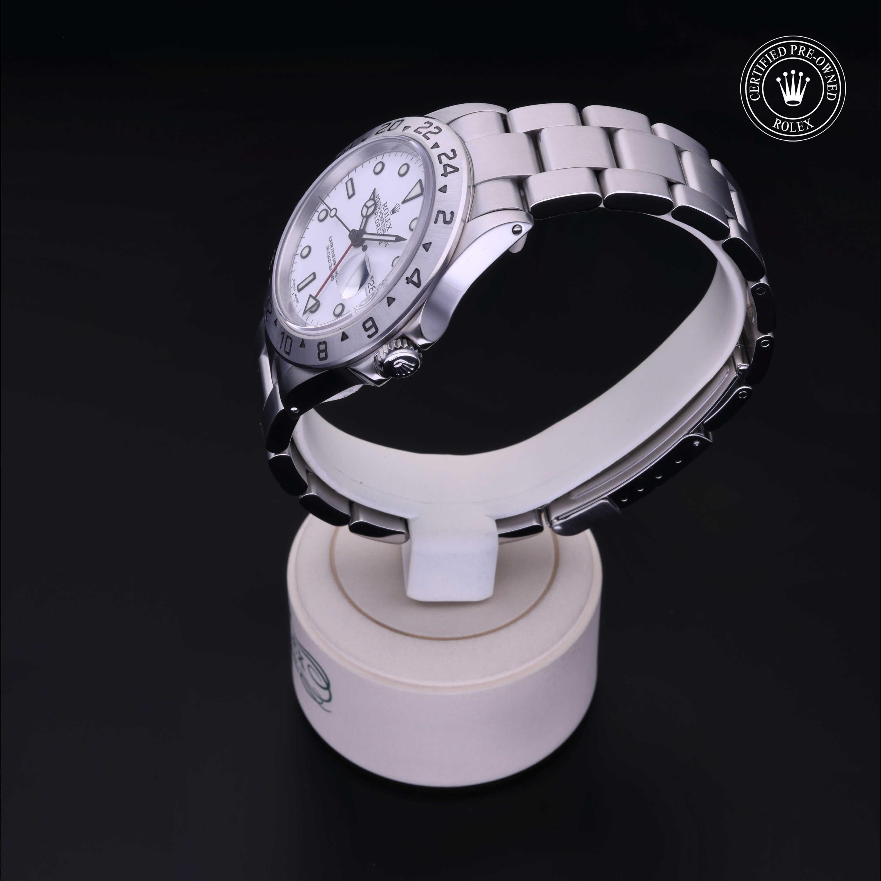 Silver Rolex luxury watch with a white dial and metal link bracelet displayed on a white stand, highlighting its certified pre-owned status and fine craftsmanship.