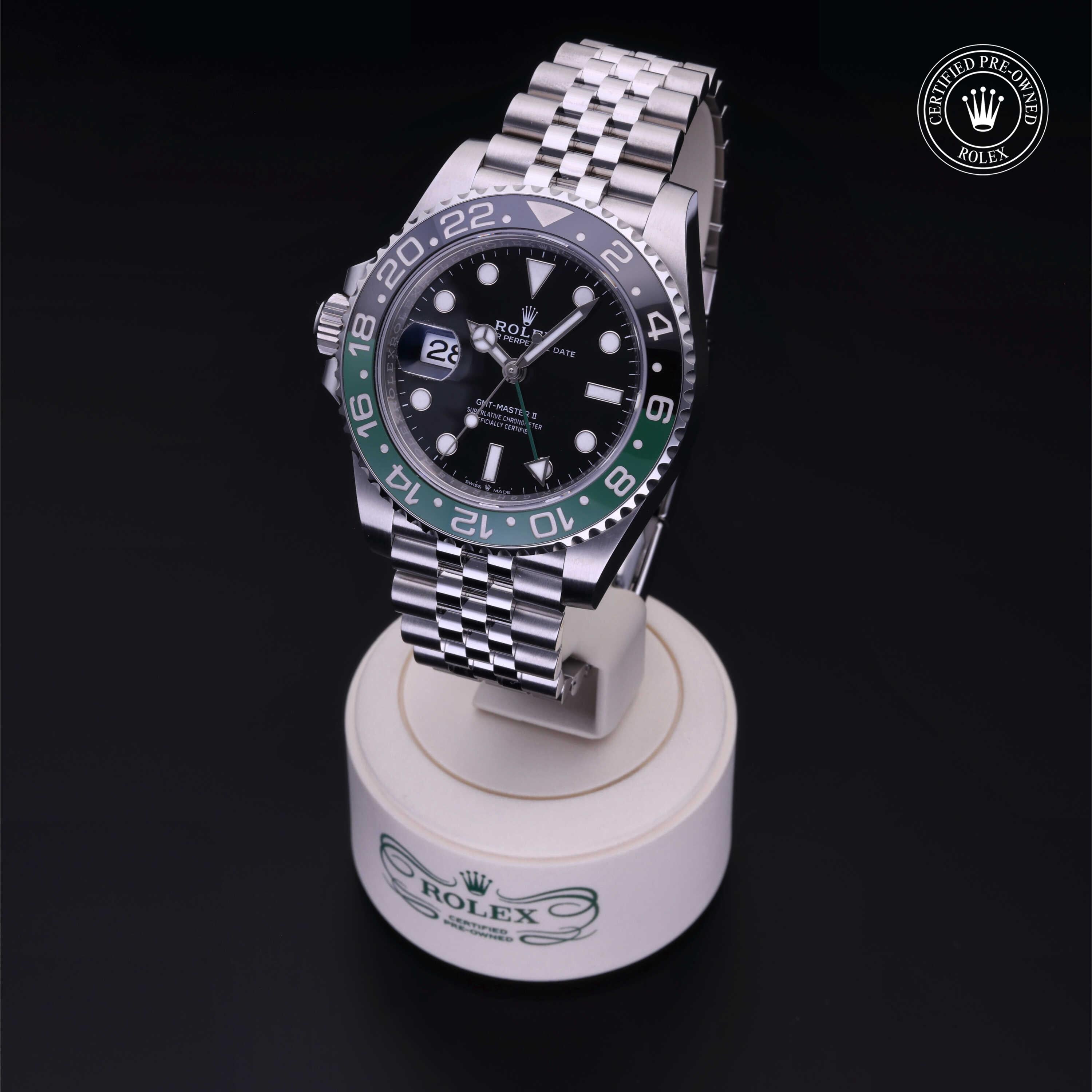 Rolex GMT-Master II with black and green ceramic bezel and Jubilee bracelet displayed on a branded white stand, highlighting luxury watch craftsmanship and Rolex certified pre-owned quality.