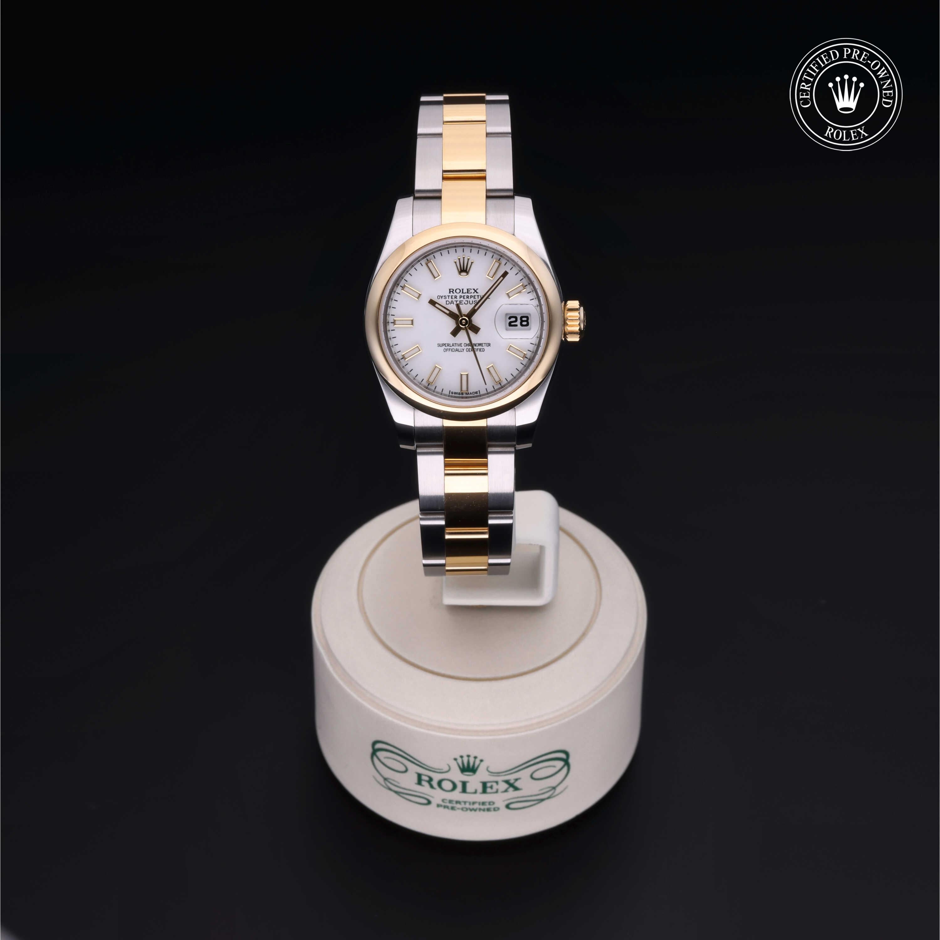Two-tone Rolex wristwatch with gold and silver metal band displayed on a round white stand against a black background, featuring a white dial and date display window.