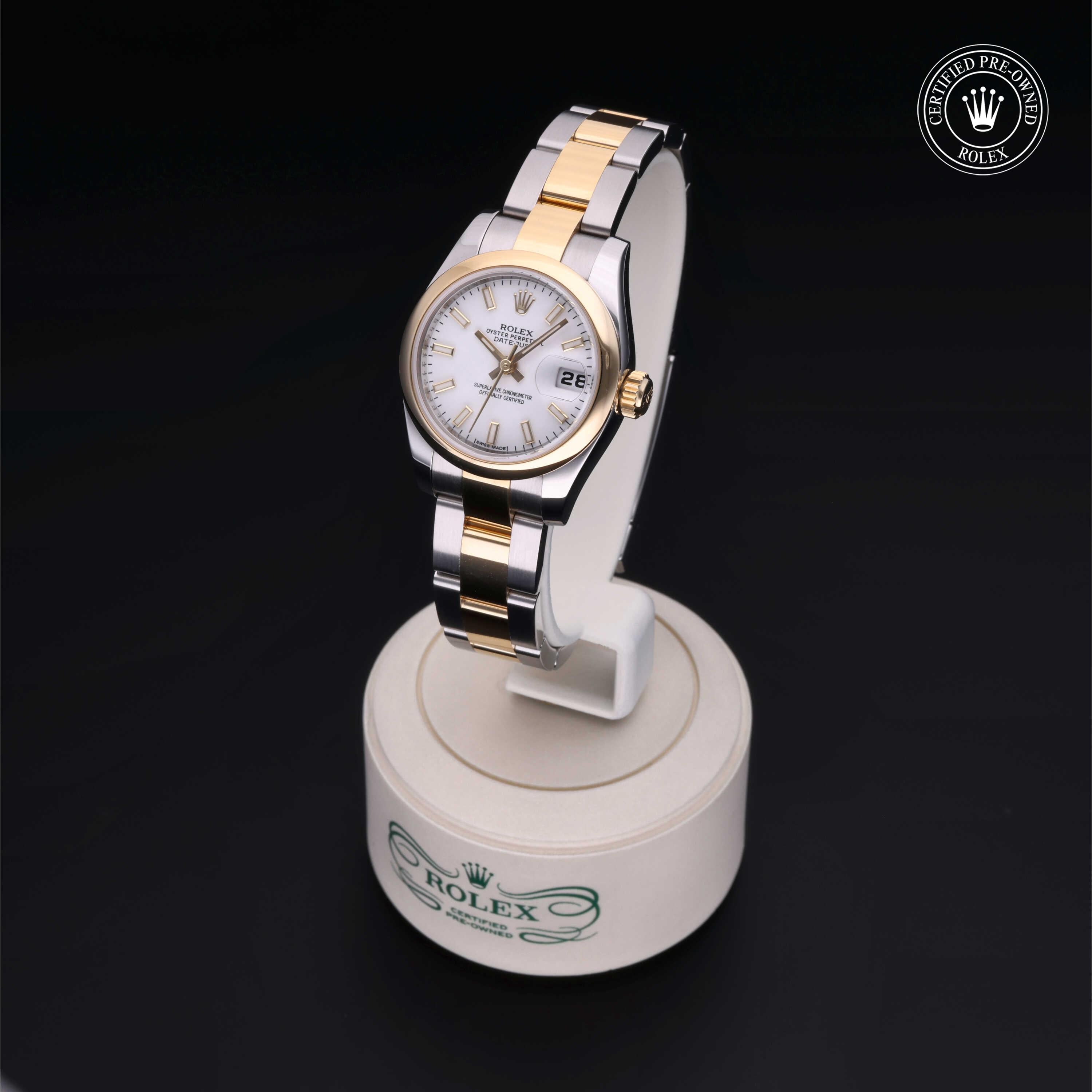 Two-tone Rolex watch with gold and stainless steel bracelet, white dial with date display on a round white stand featuring the Rolex logo and a certified pre-owned Rolex emblem in the corner.