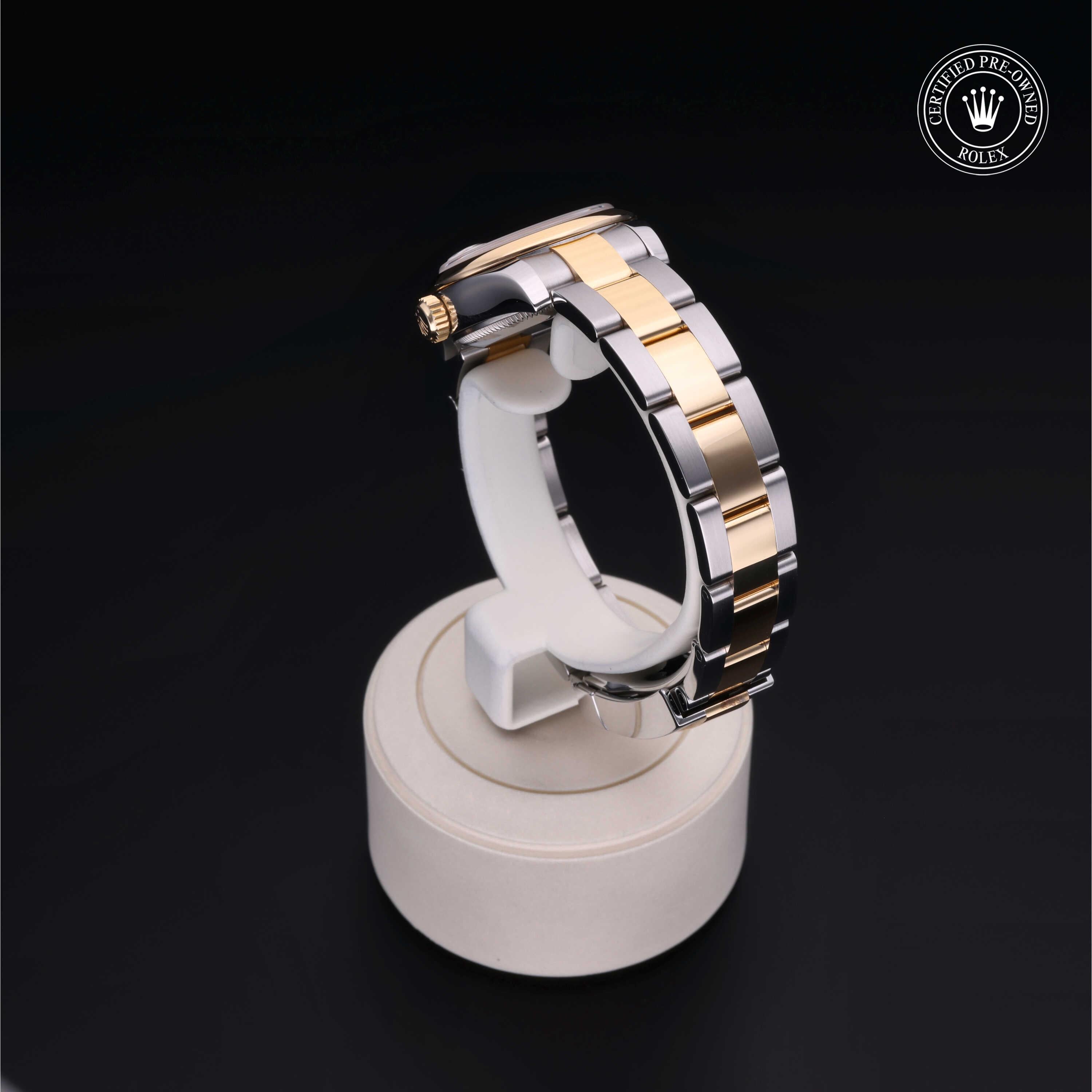 Two-tone Rolex watch band with gold and silver links displayed on a white stand against a black background, featuring a certified pre-owned Rolex logo.