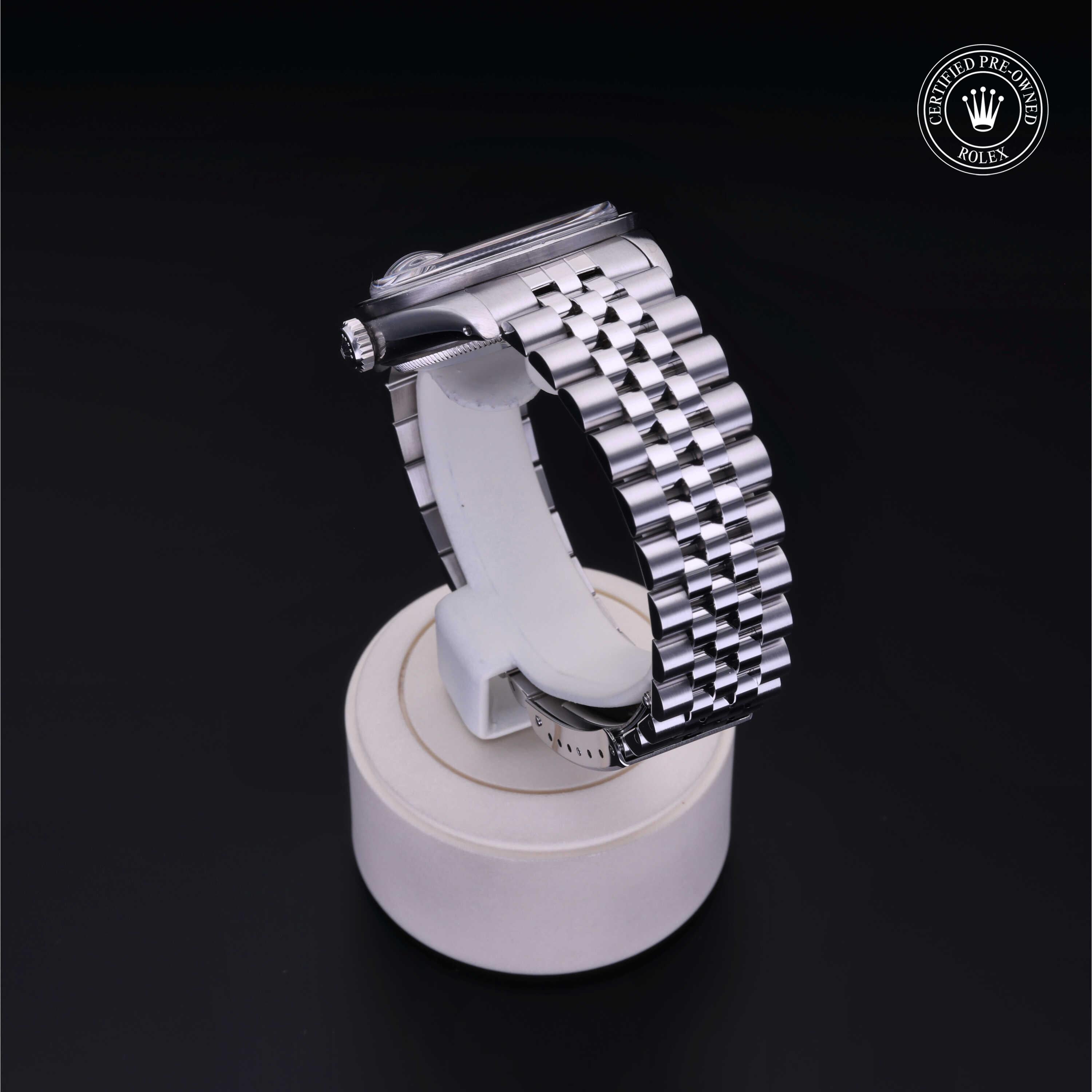 A polished silver metal watch bracelet with a Jubilee-style link design displayed on a cylindrical white stand against a black background, featuring a Rolex Certified Pre-Owned logo.