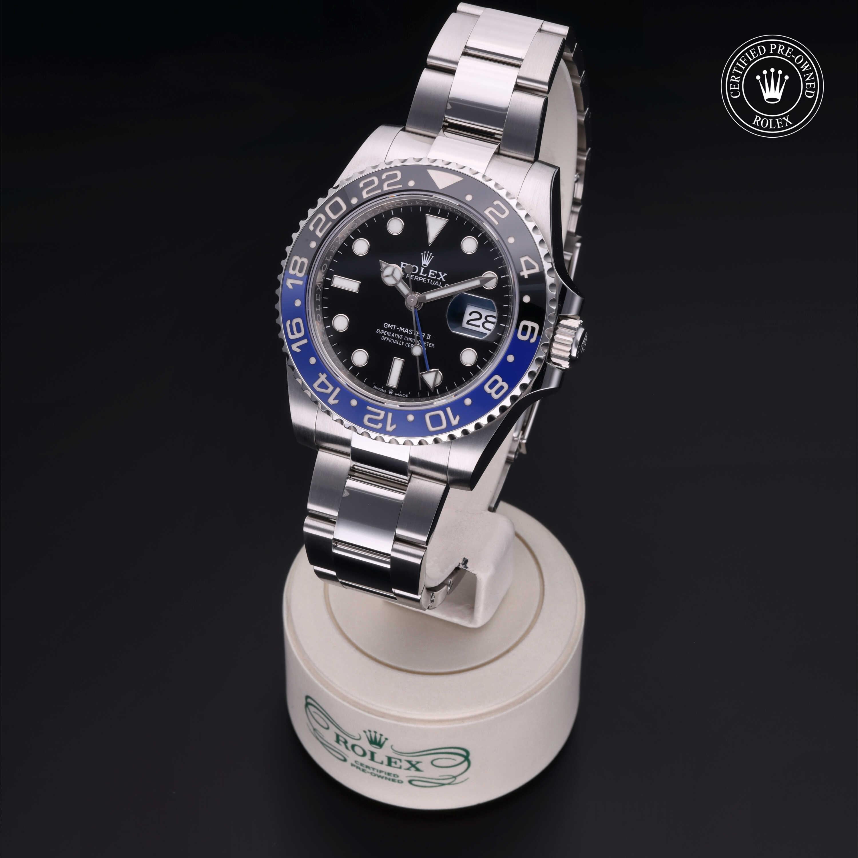 Rolex Certified Pre-Owned luxury watch with a black and blue bezel and stainless steel bracelet displayed on a branded stand, highlighting fine craftsmanship and design.