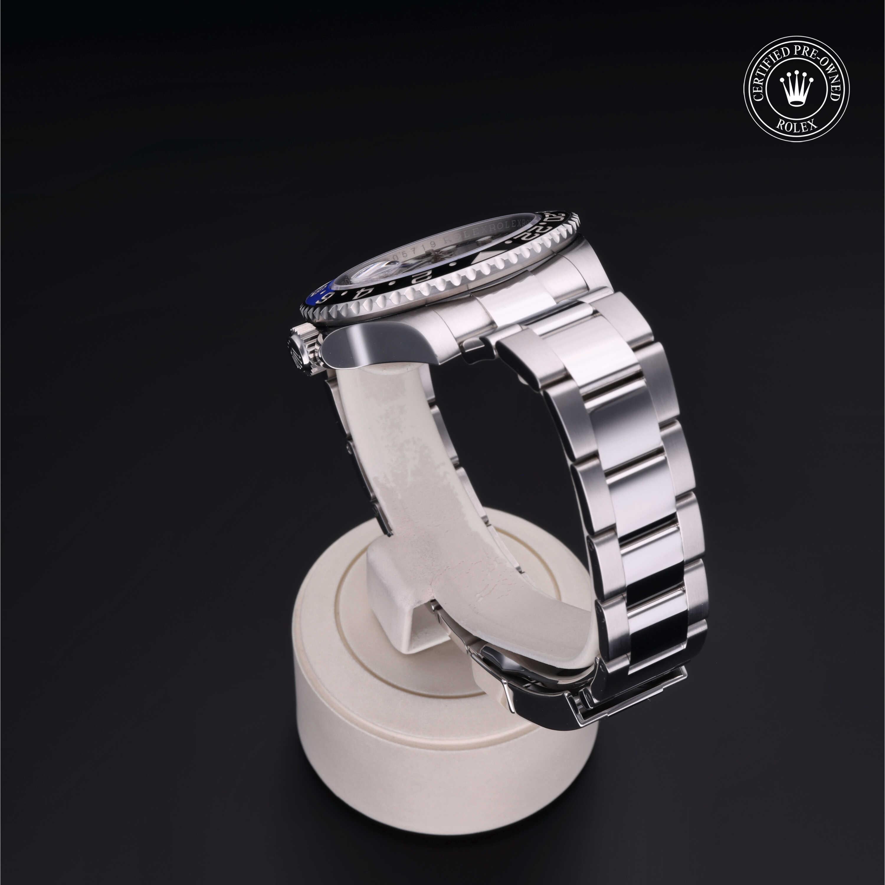 Side view of a polished luxury watch with a stainless steel bracelet displayed on a white stand against a black background, featuring a certified pre-owned Rolex emblem.
