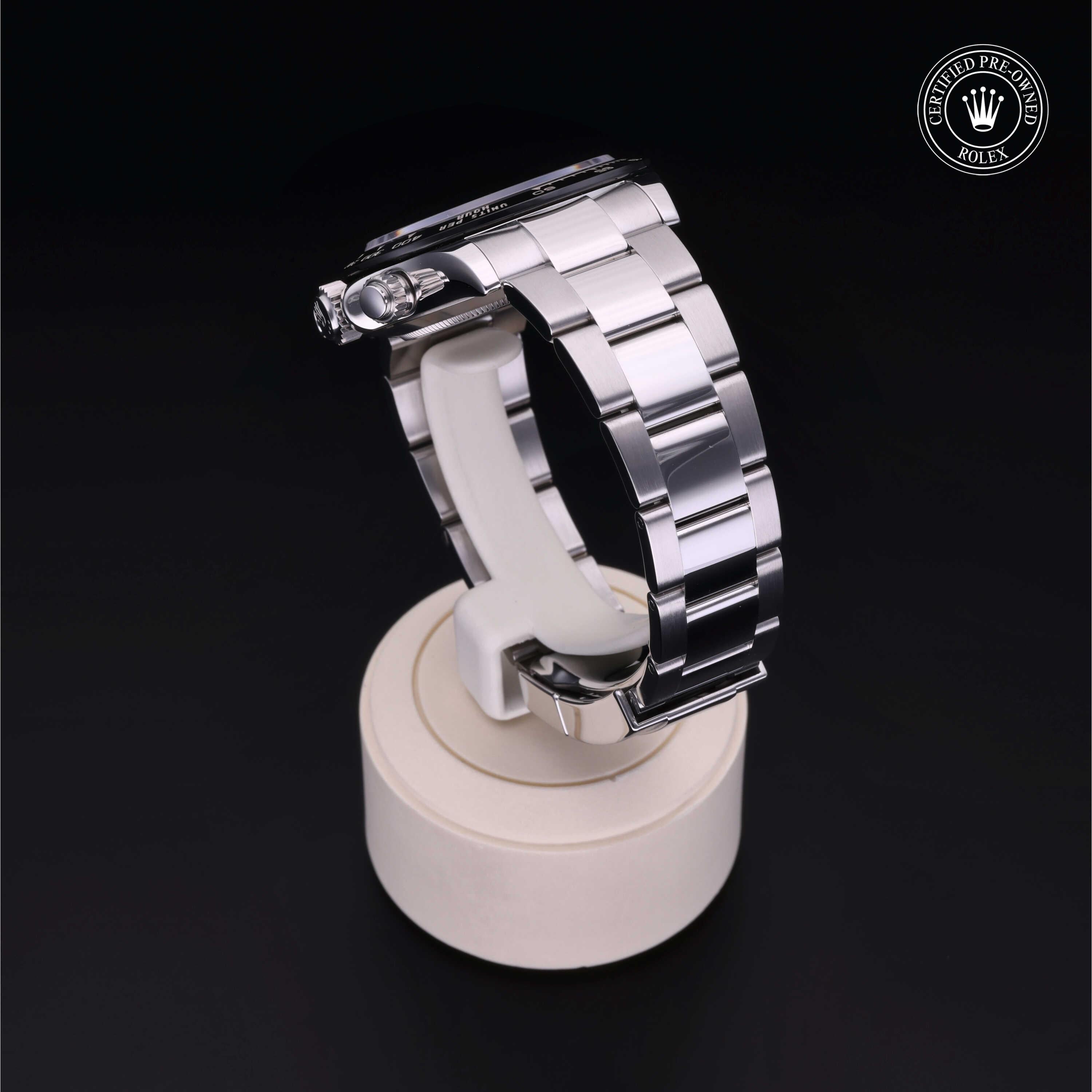 Silver metal link Rolex watch displayed on a white stand against a black background with a certified pre-owned Rolex logo in the top right corner.