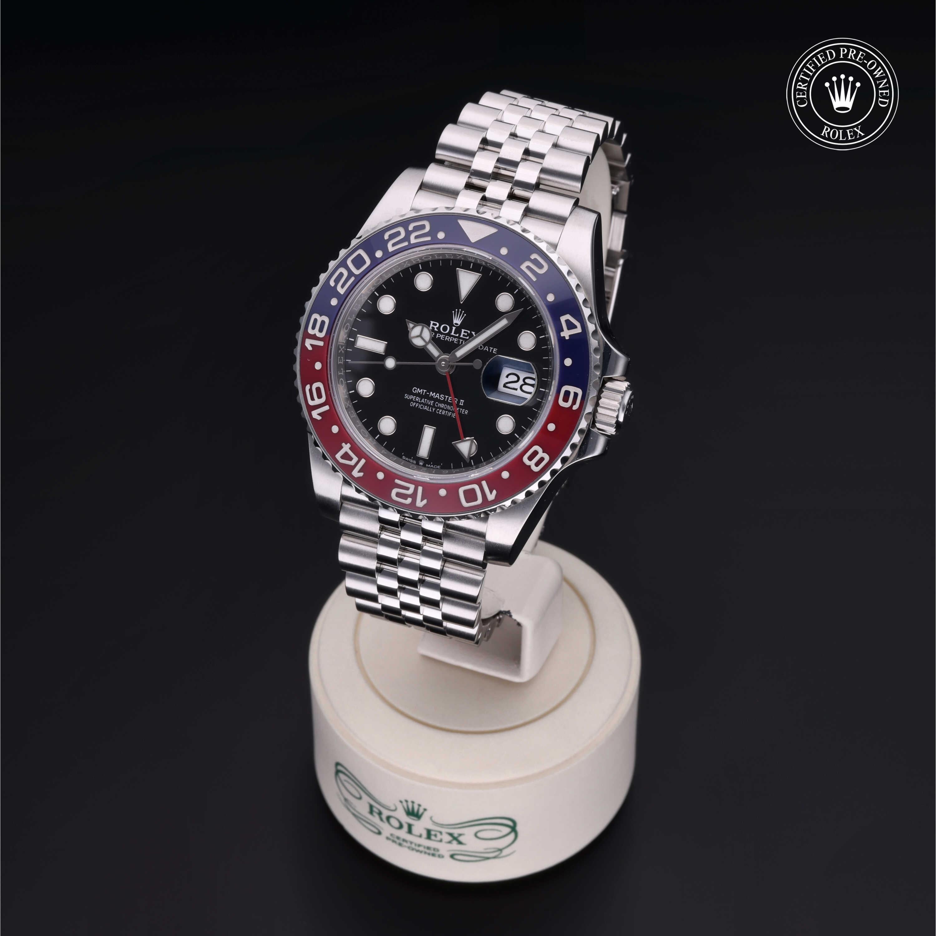 Rolex GMT-Master II with red and blue bezel and Jubilee bracelet displayed on a branded stand, featuring Rolex Certified Pre-Owned logo in the corner.