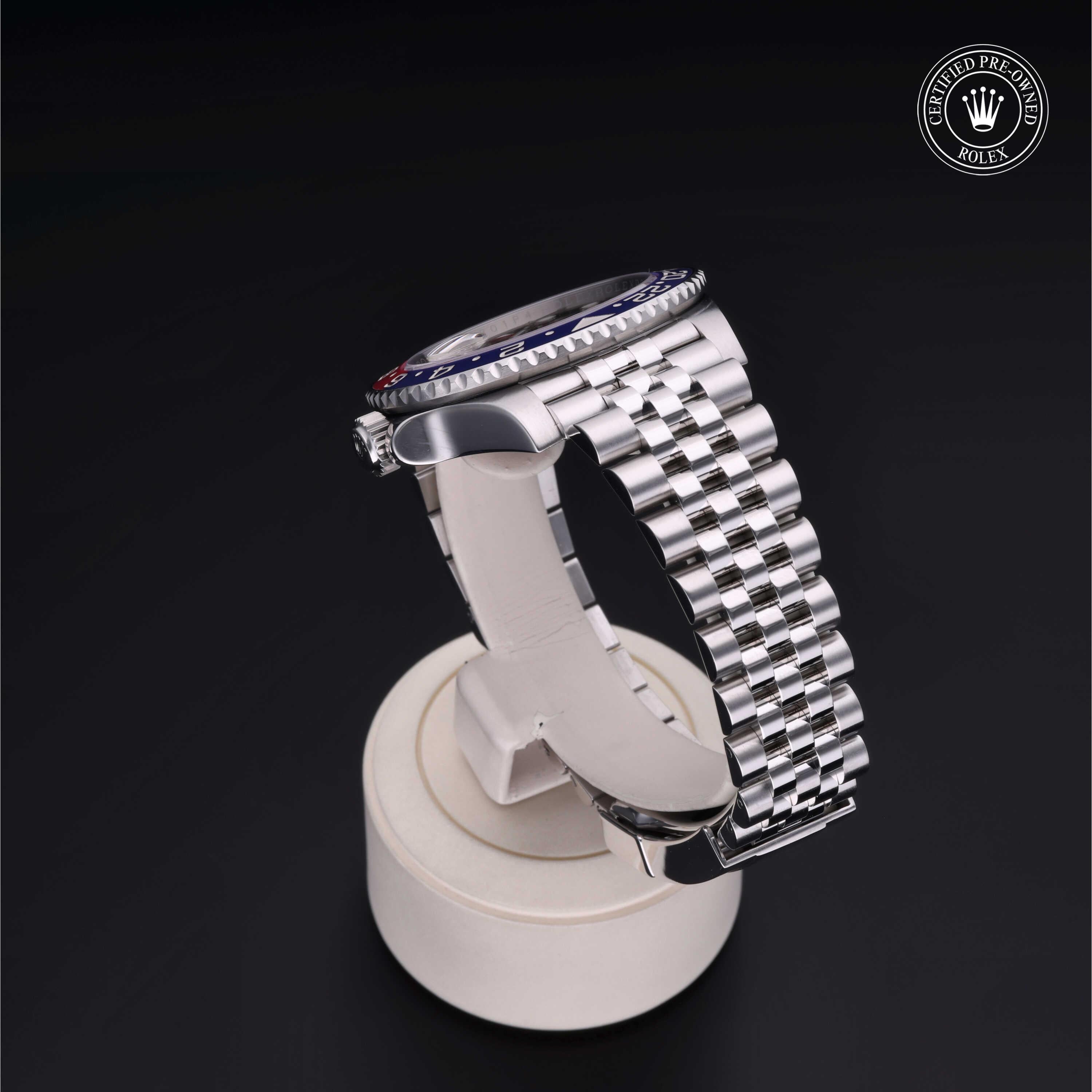 Side view of a luxury silver Rolex watch with a metal link bracelet displayed on a white stand against a black background, featuring a certified pre-owned logo.