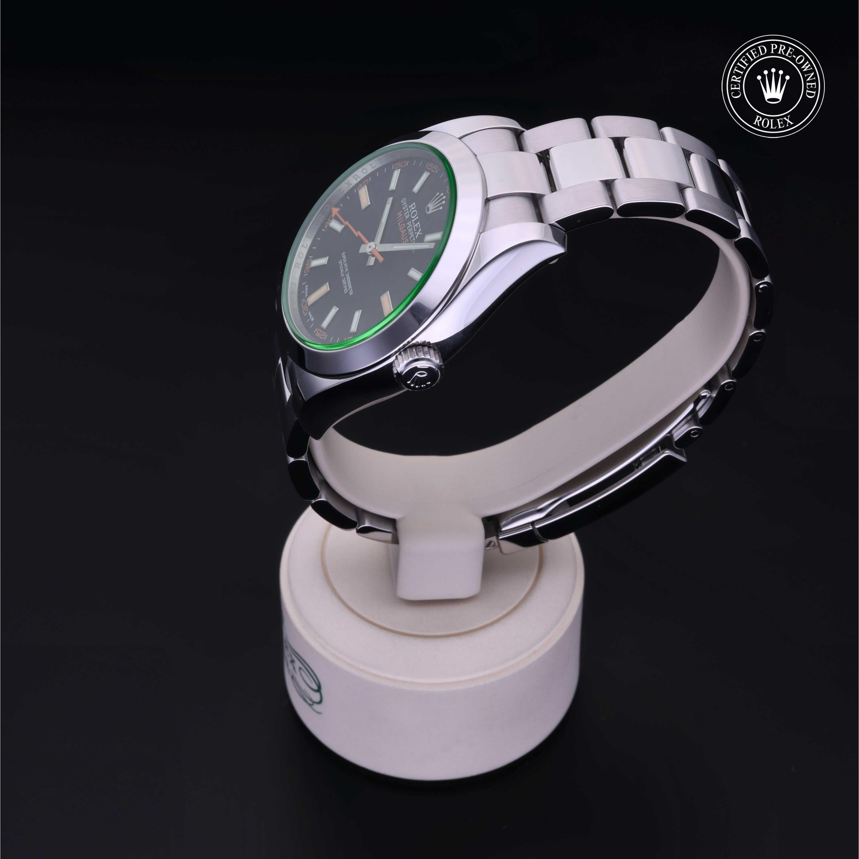 Silver Rolex watch with a green bezel displayed on a white stand against a black background, featuring a certified pre-owned Rolex logo in the corner.