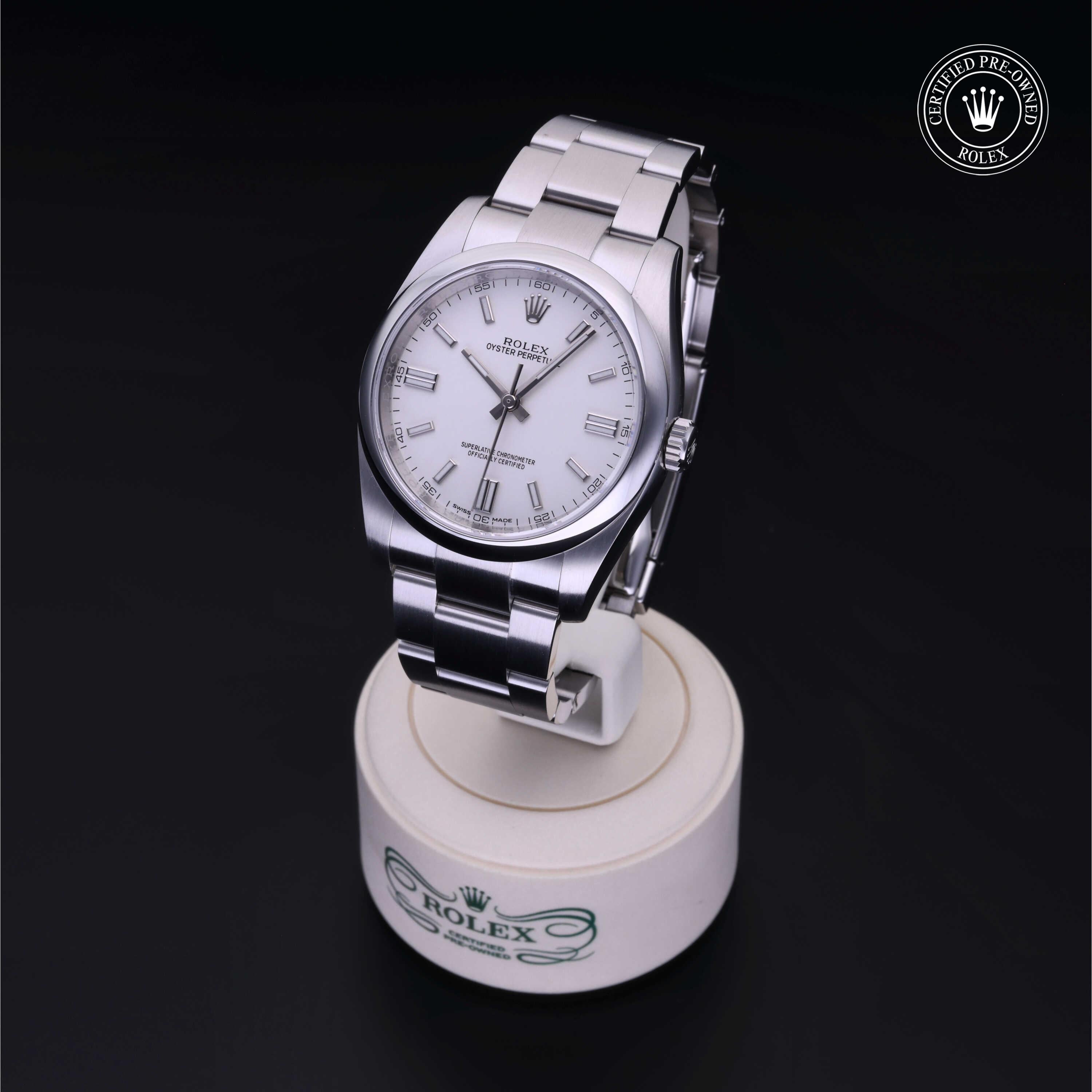 Silver Rolex luxury watch with a white face and metal band displayed on a branded stand with a 