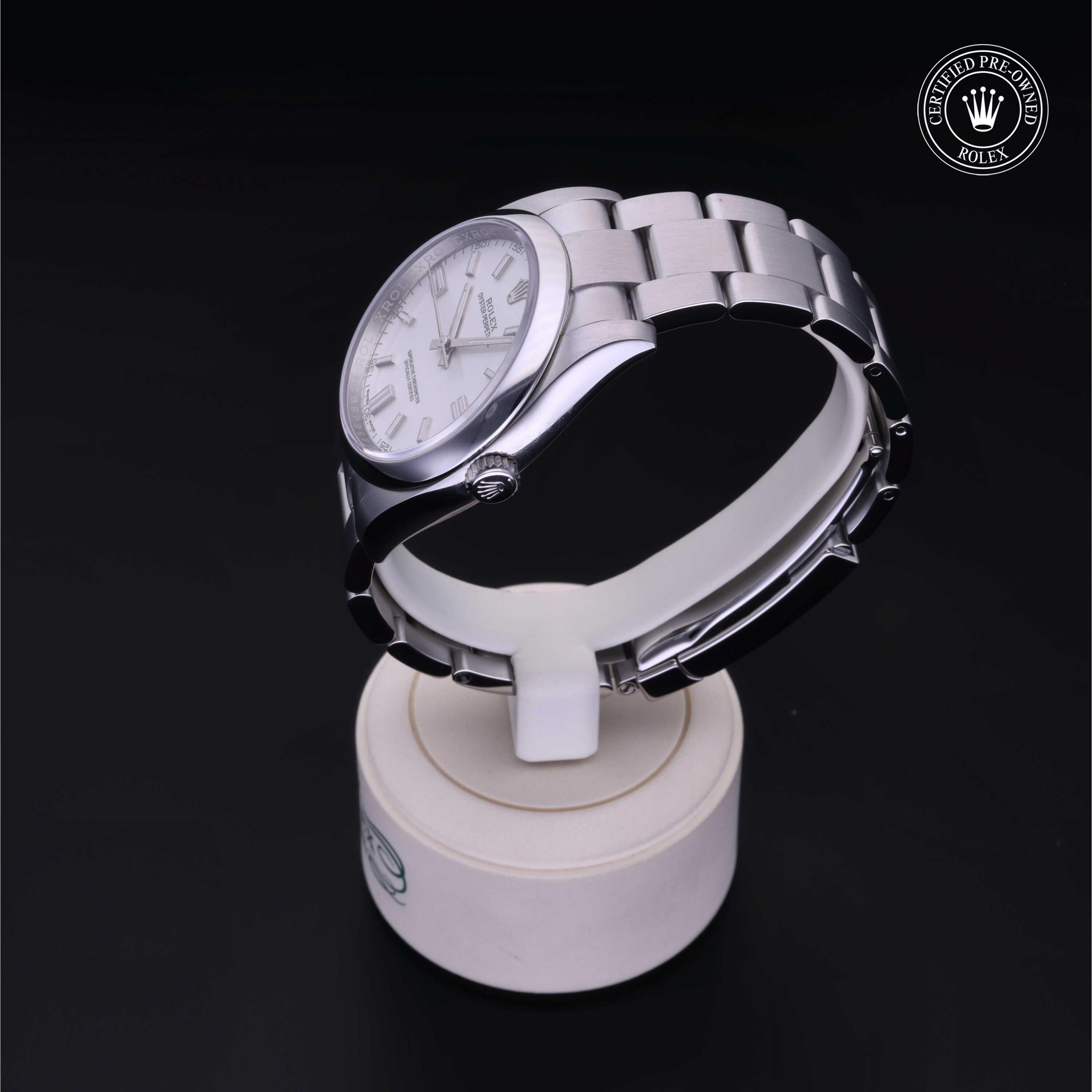 Silver stainless steel Rolex luxury watch with a white dial and metal link bracelet displayed on a white stand against a black background, featuring a certified pre-owned emblem.