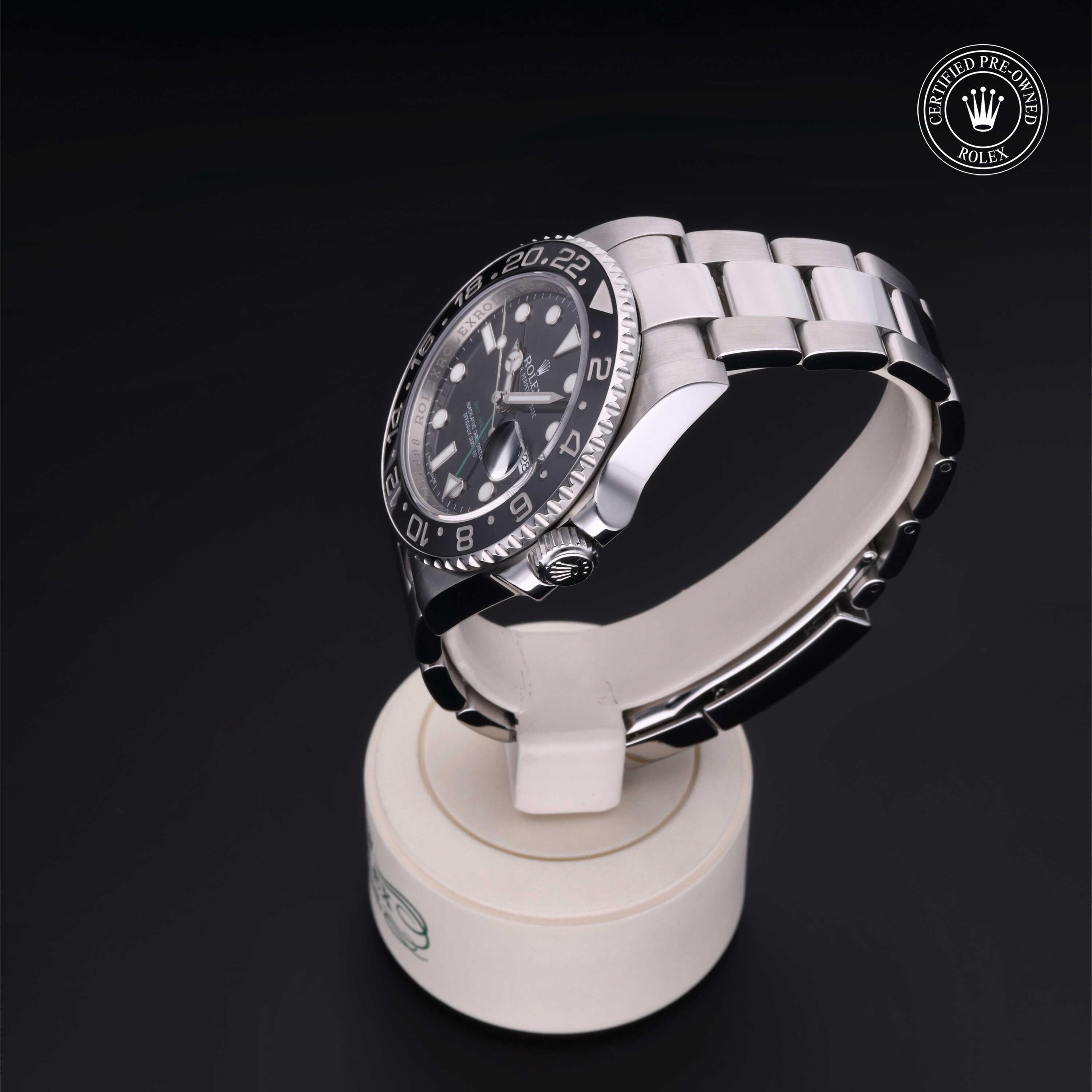 Luxury stainless steel Rolex watch with black dial and bezel, displayed on a white stand against a dark background, featuring a certified pre-owned Rolex logo.