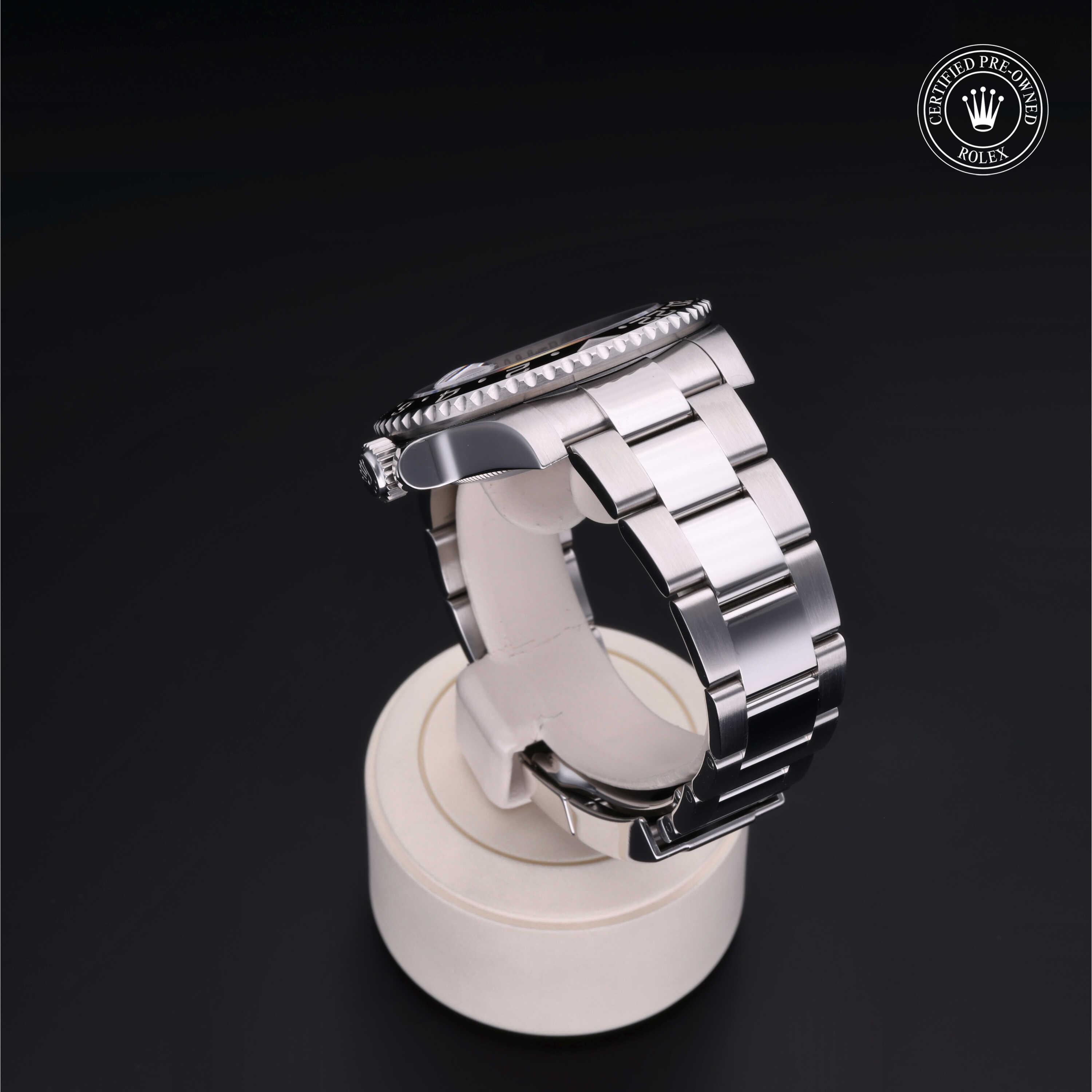 Side view of a polished stainless steel Rolex watch with a metal link bracelet displayed on a round white stand against a black background, featuring a Certified Pre-Owned Rolex logo.