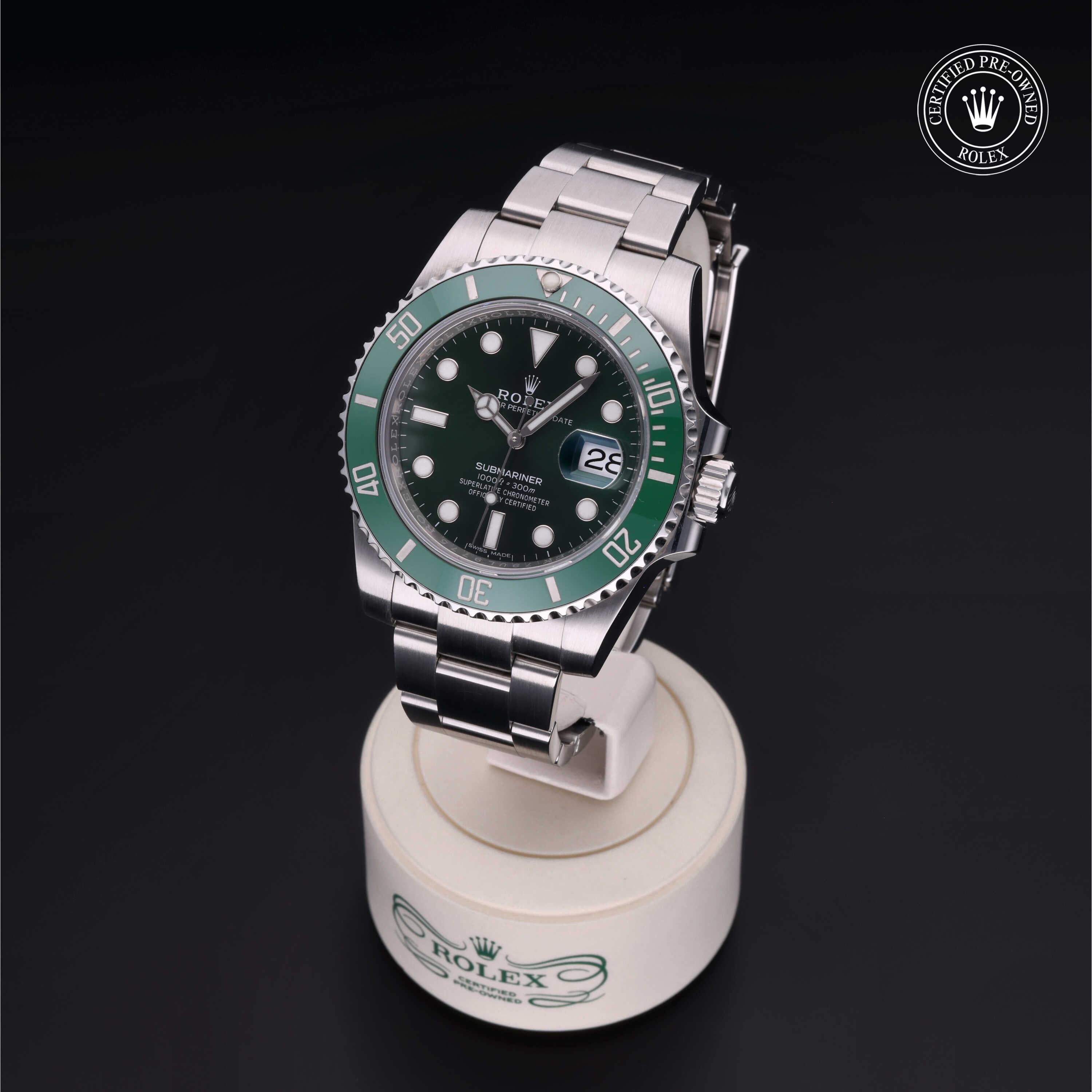 Rolex Submariner wristwatch with green bezel and black dial displayed on a branded stand, featuring Rolex Certified Pre-Owned logo on a dark background.