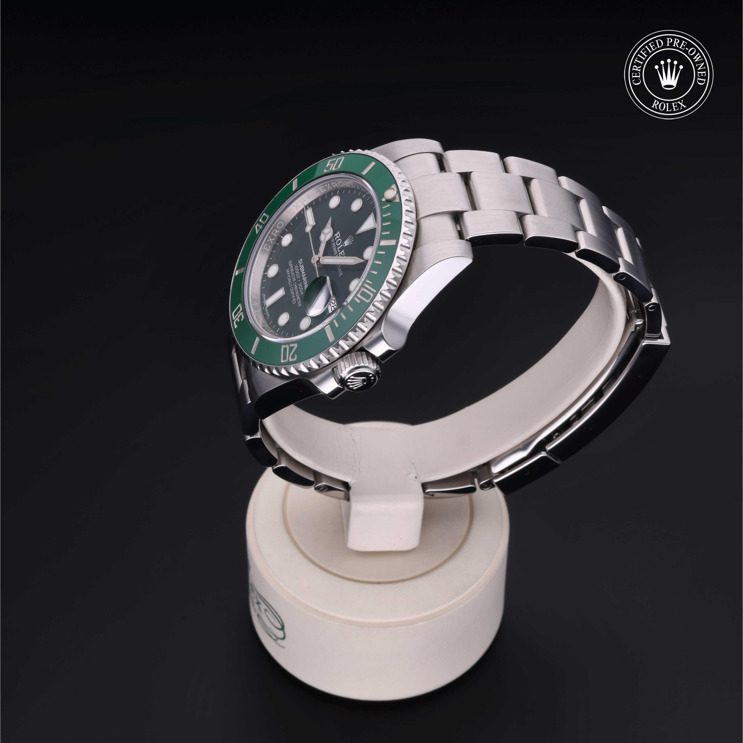 Rolex Certified Pre-Owned luxury watch with stainless steel bracelet and green bezel, displayed on a white stand against a black background by a family-owned jeweler.