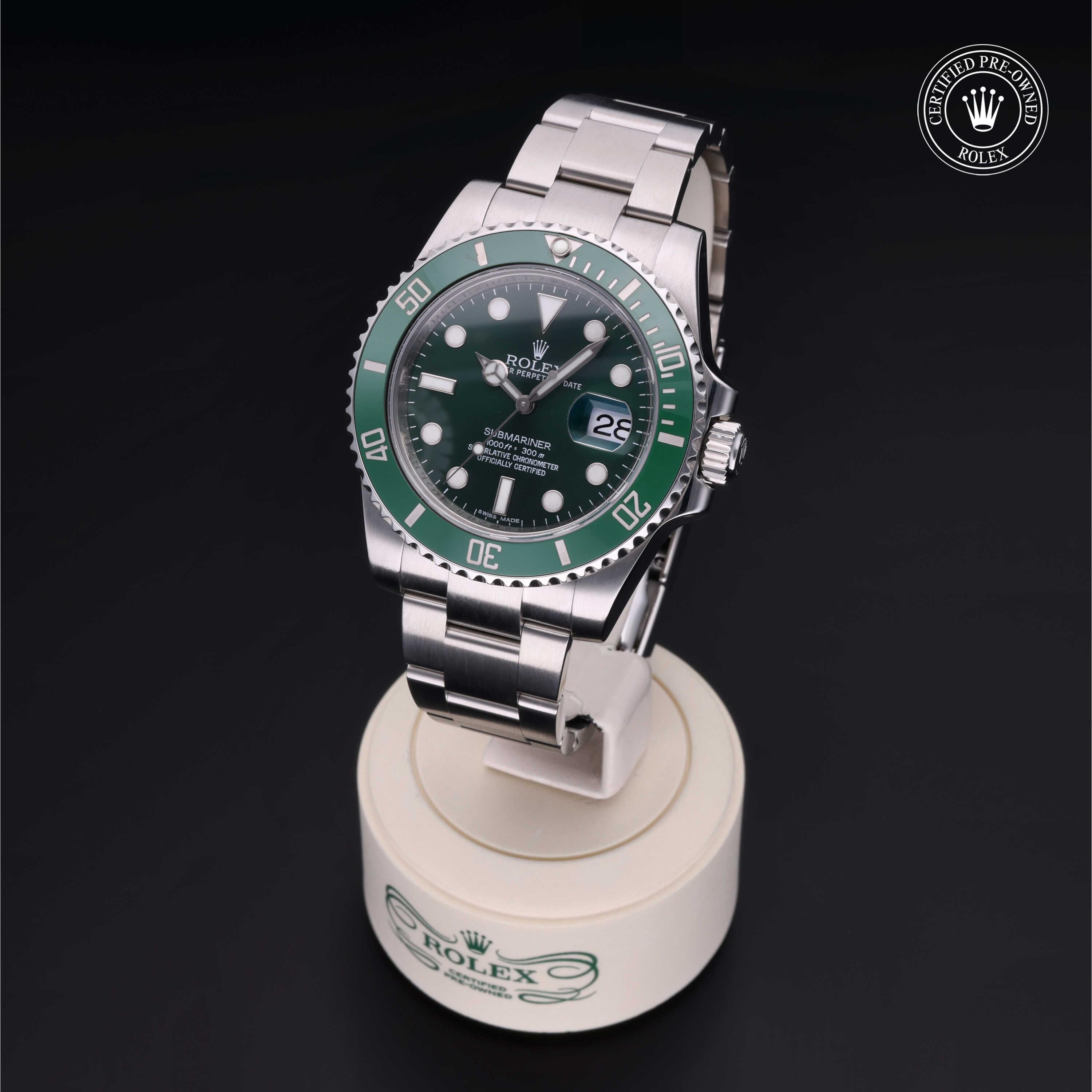 Silver Rolex Submariner watch with a green bezel and dial displayed on a white stand against a black background, featuring the certified pre-owned Rolex logo.
