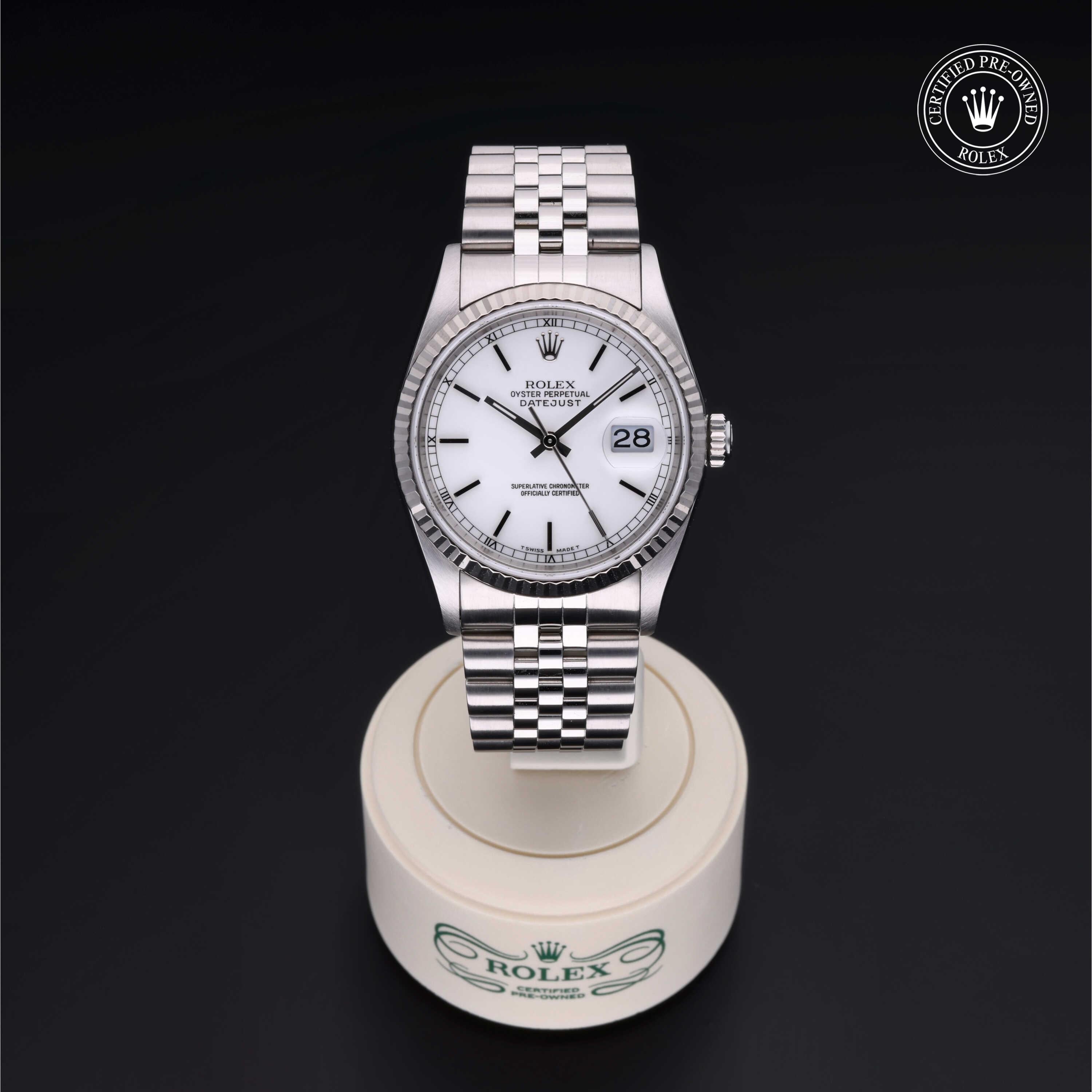 Rolex stainless steel wristwatch with a white dial and date display on a white Rolex stand, featuring a certified pre-owned Rolex logo in the corner.