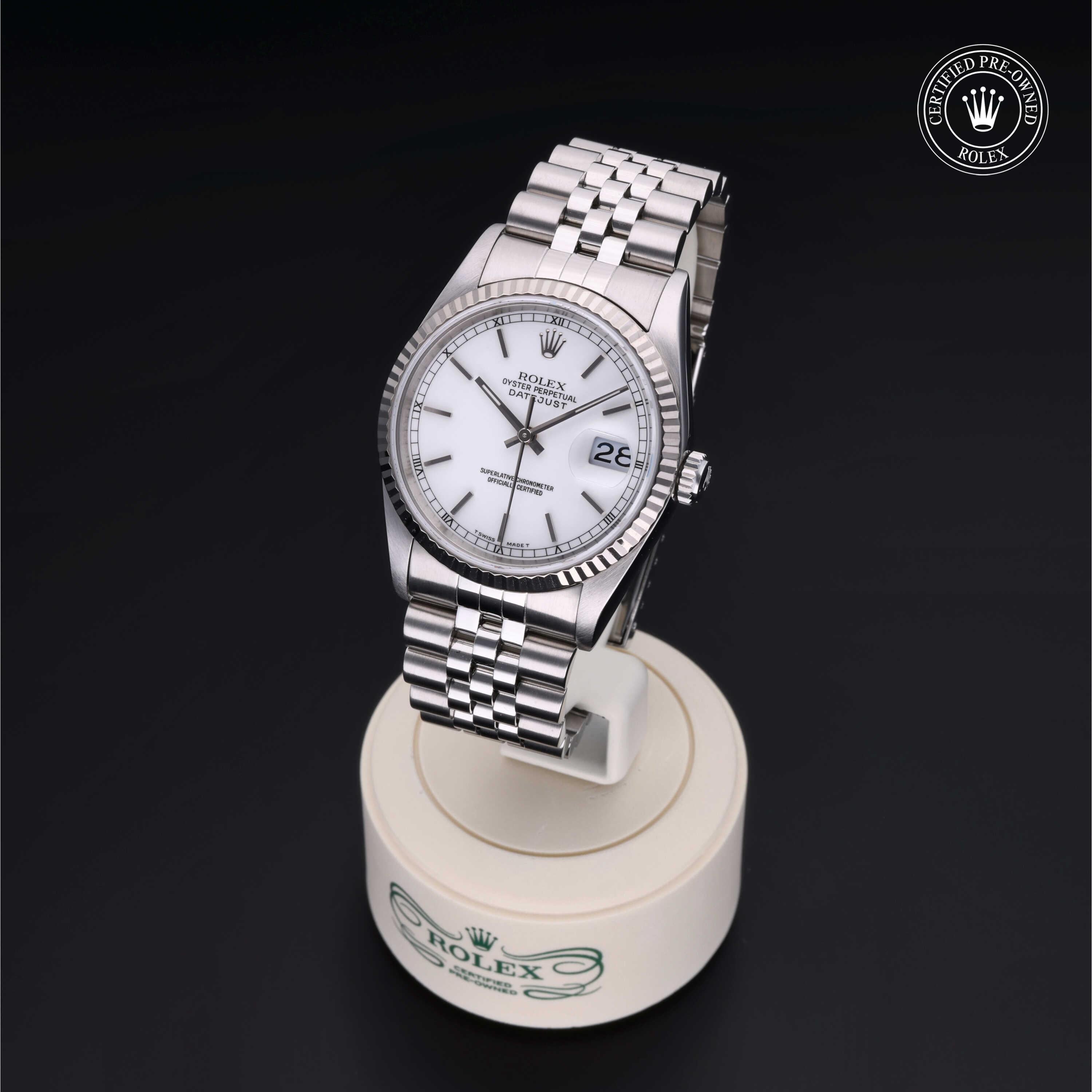 Silver Rolex wristwatch with white dial, date display, and fluted bezel resting on a branded round stand against a black background, featuring a Certified Pre-Owned Rolex logo.