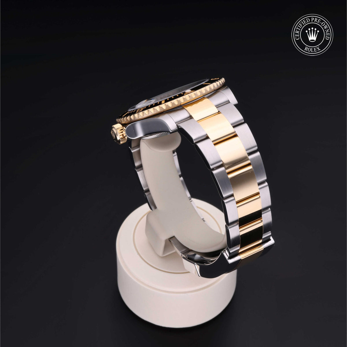Close-up of a two-tone luxury watch with gold and silver links on a white display stand against a black background featuring a Rolex Certified Pre-Owned logo.