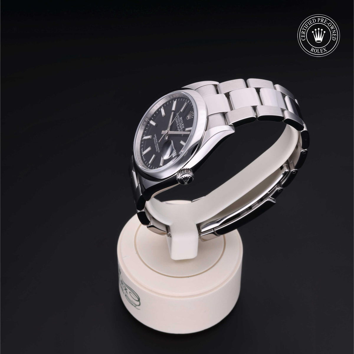 Silver Rolex luxury watch with black dial displayed on a white stand, featuring the Rolex Certified Pre-Owned logo on a dark background, showcasing fine watch craftsmanship.