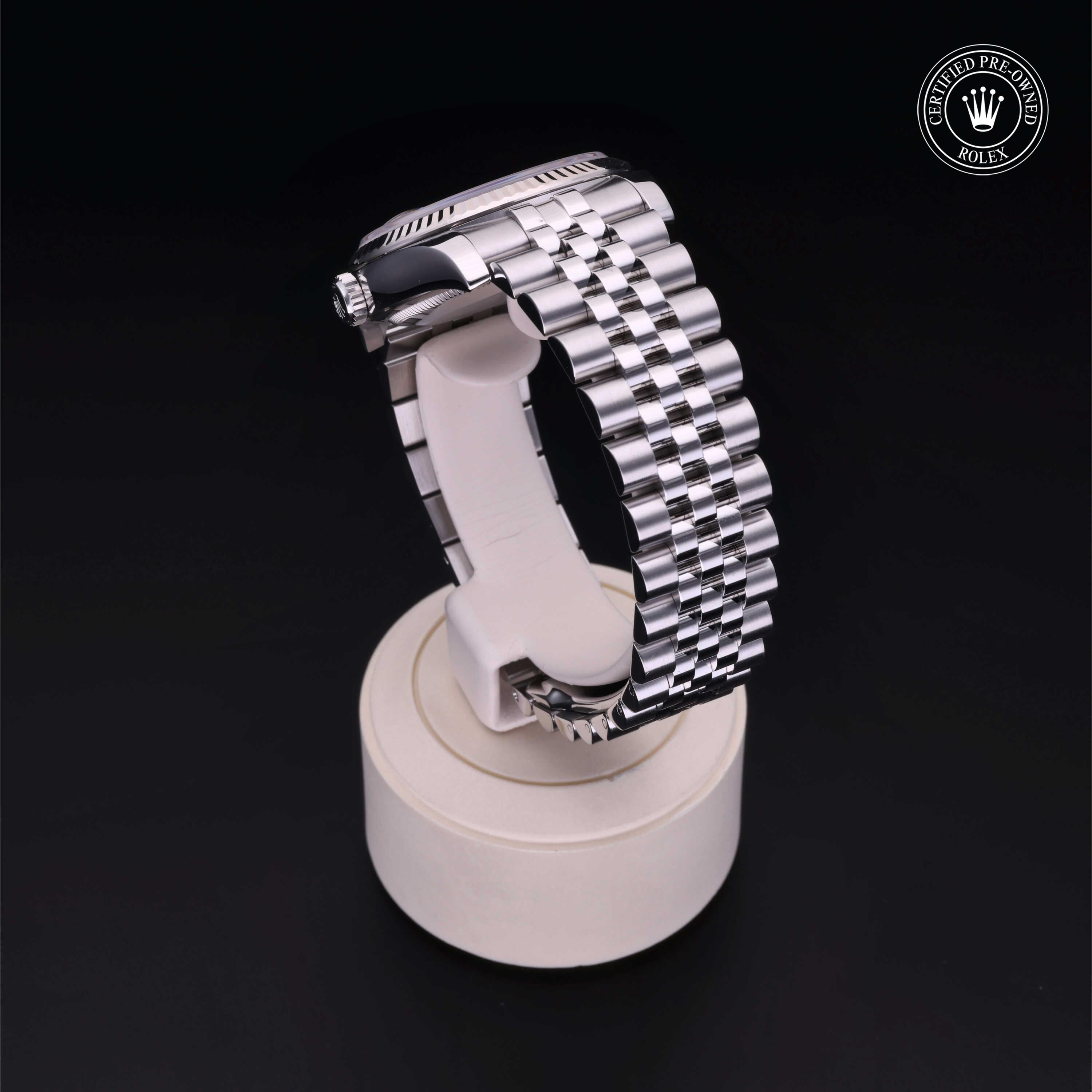 Silver metal luxury watch with a polished link bracelet displayed on a white stand against a black background, featuring a Rolex Certified Pre-Owned logo in the corner.