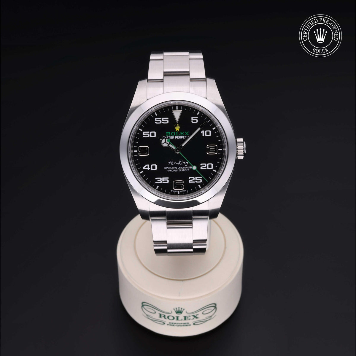 Rolex Air-King luxury watch with black dial and stainless steel bracelet displayed on a branded white stand, featuring a certified pre-owned Rolex emblem.
