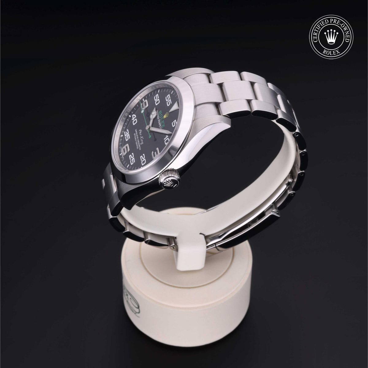 Stainless steel Rolex luxury watch with a black dial and silver hour markers displayed on a white stand, featuring the Rolex Certified Pre-Owned logo.