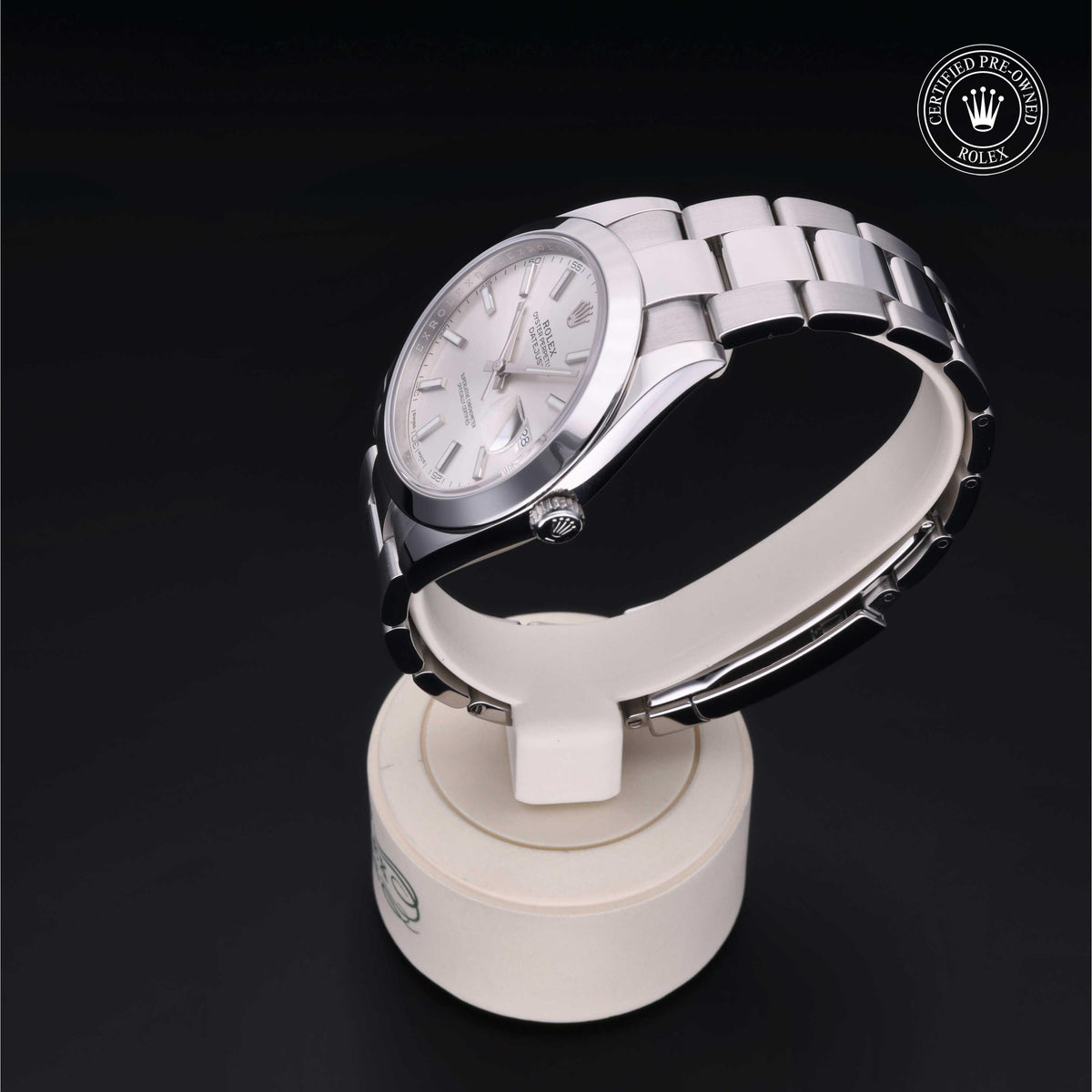 Silver stainless steel Rolex wristwatch with white dial and metal link bracelet displayed on a white circular stand against a black background featuring a certified pre-owned Rolex logo.