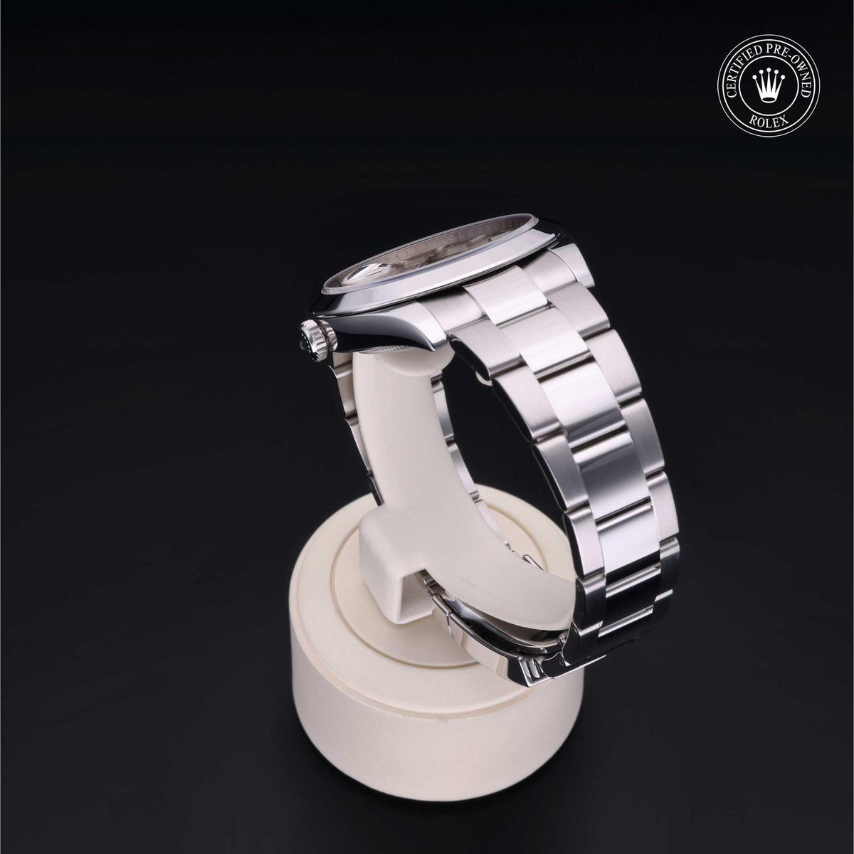 Silver stainless steel luxury watch displayed on a white stand against a black background with a Rolex Certified Pre-Owned logo in the corner.