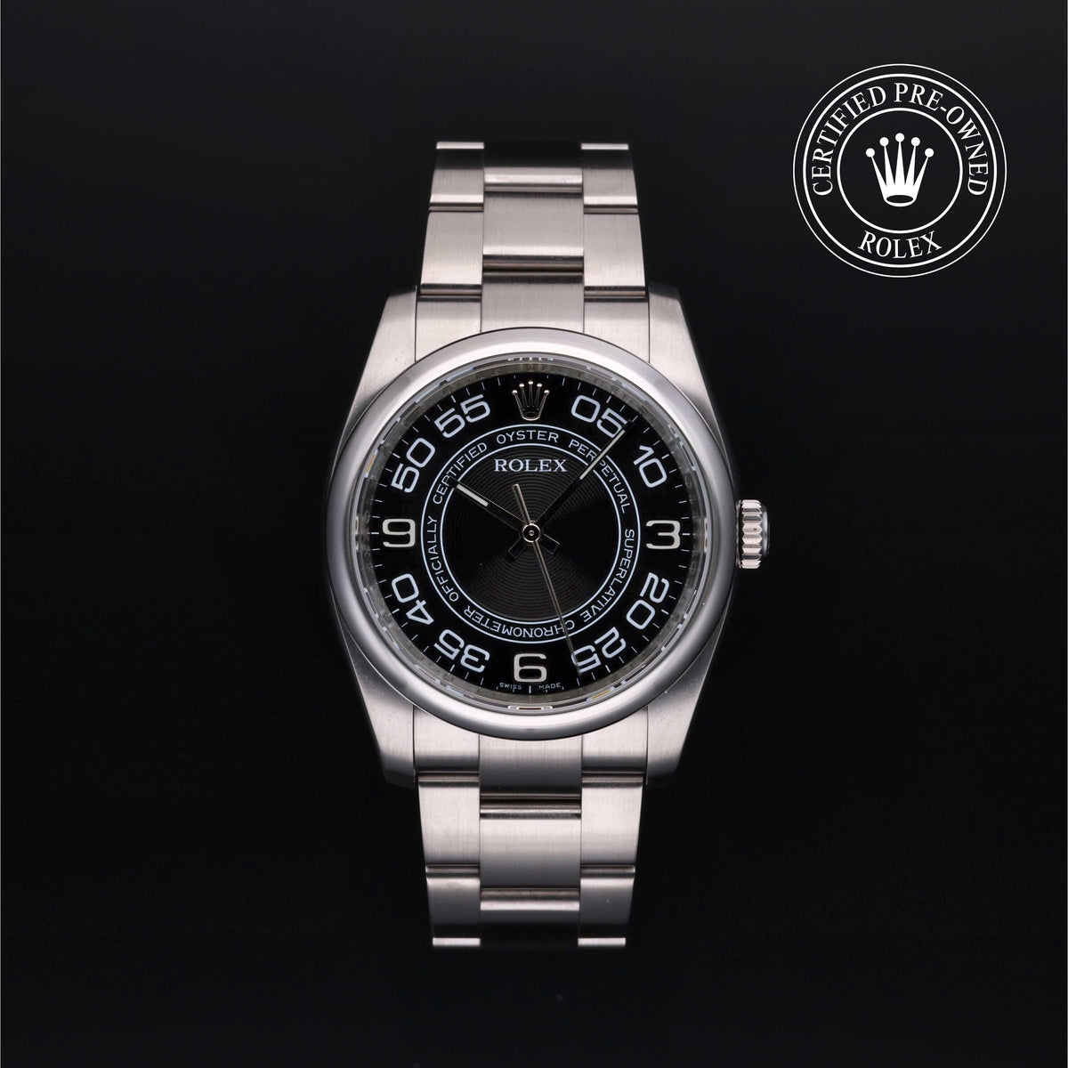 A Rolex Oyster Perpetual watch with a stainless steel bracelet and a black dial featuring white Arabic numerals, shown against a black background with a 'Certified Pre-Owned Rolex' emblem in the top right corner.