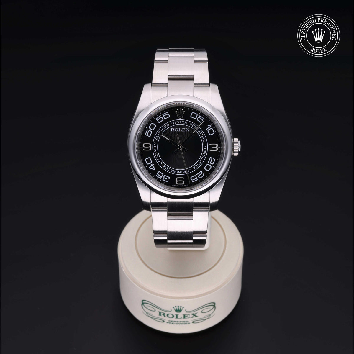 Silver Rolex wristwatch with a black dial featuring large numerals, displayed on a branded stand with a Certified Pre-Owned Rolex logo in the top corner.
