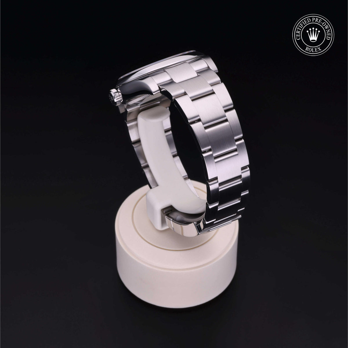 Close-up of a polished stainless steel Rolex watch bracelet displayed on a white stand against a black background with a Rolex Certified Pre-Owned logo in the corner.